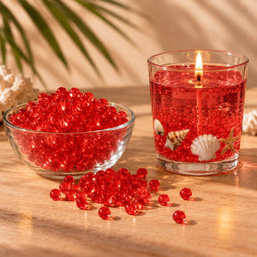 Perle di cera gel rossa per candele in una ciotola e candela gel rossa accesa con conchiglie