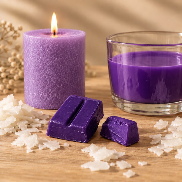 Blocchetti di colorante solido viola per candele accanto a una candela a colonna e cera fusa colorata di viola