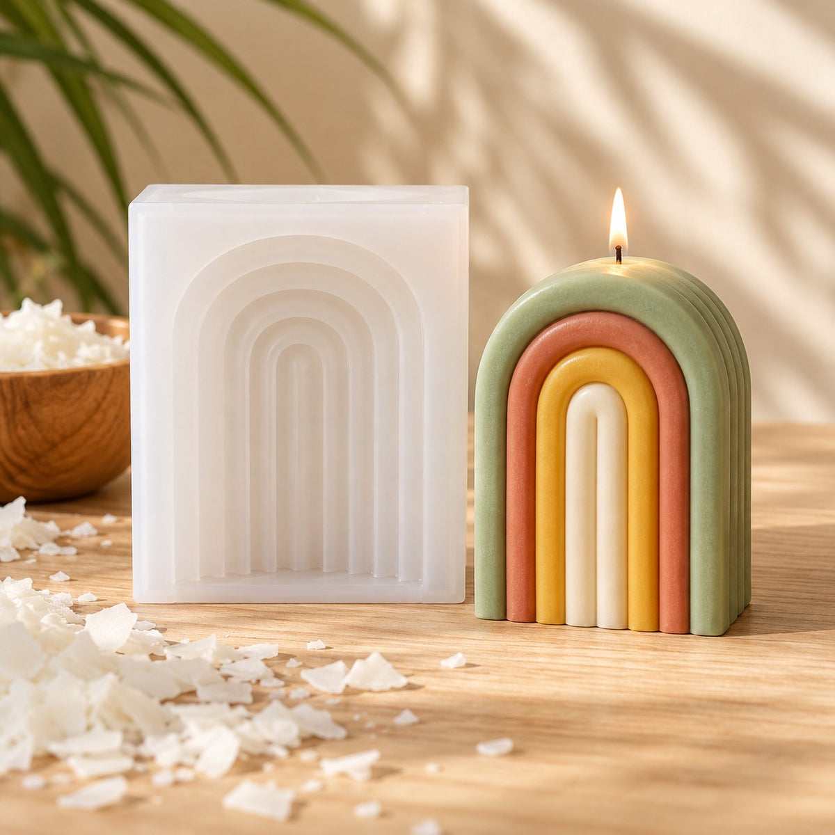 Molde de silicona para vela arcoíris junto a una vela de arco en capas de colores encendida - Naturcera