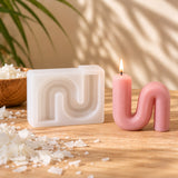 Molde de silicona para velas con forma curva U y vela ondulada rosa encendida - Naturcera